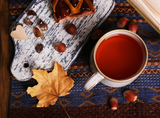 Cup of tea with autumn decor on wooden table.