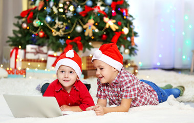 Two cute small brothers using laptop on Christmas decoration background