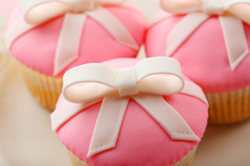 Tasty cupcakes with bow on color wooden background