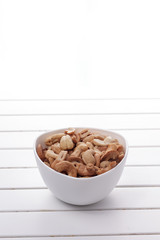 Pile of cashew nuts in a bowl on white wooden table