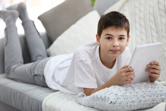 Little boy using tablet on a sofa at home