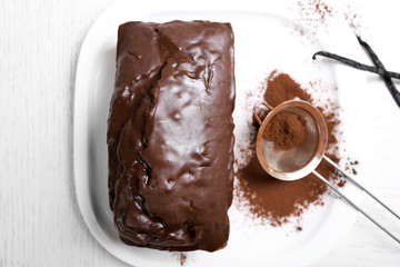 Chocolate cake with icing and cocoa powder on white table