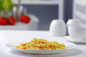 Stewed rice with a carrot on a white plate
