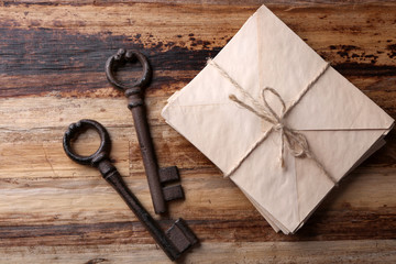 Old keys with pile of papers on  wooden background, close up