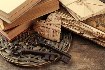 Composition of old books, keys and other things with wicker plate on wooden background, close up