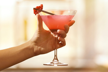 Main féminine avec verre de cocktail sur fond de bar