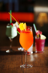 Glasses of cocktails on bar background