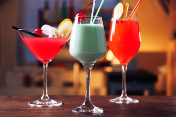 Glasses of cocktails on bar background