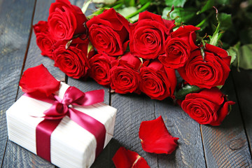 Obraz na płótnie Canvas Bouquet of fresh red roses and present box on wooden background