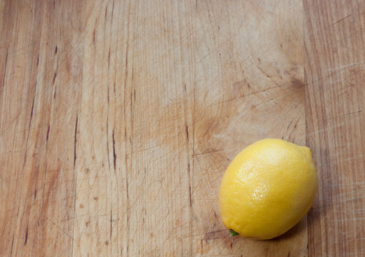 Lemon On Bottom Right Corner Of Well-worn Butcher Block With Wood Planks In Vertical Pattern