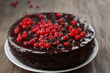 Chocolate cake with cranberries on wooden table, closeup