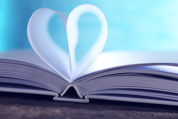 Heart from book pages on blue blurred background