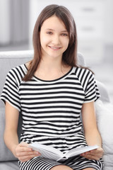 Beautiful girl reading book on sofa, indoor