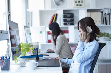 Naklejka premium Women have to work while talking on a mobile phone in the office