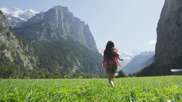 Free happy woman running in joyful freedom nature excited of joy and happiness. Cheerful active lifestyle with girl having fun in Lauterbrunnen valley, Swiss Alps, Switzerland. SLOW MOTION RED EPIC.