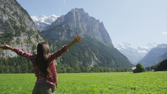 Happy free woman with arms outstretched in freedom nature excited of joy happiness. Cheerful active lifestyle with girl serene rasing arms in Lauterbrunnen valley, Swiss Alps, Switzerland. SLOW MOTION