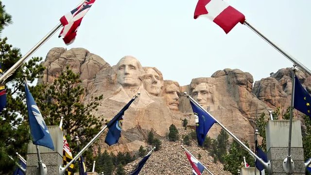 State flags waving in the wind with Mount Rushmore in the background in South Dakota
