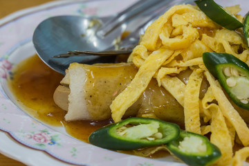Close up of spring rolls with sweet sauce, vegetables and in noodle tube.