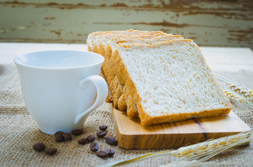 whole wheat bread and coffee on wooden board (bread focus)