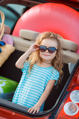 Portrait of a little girl sitting in the trunk of a car