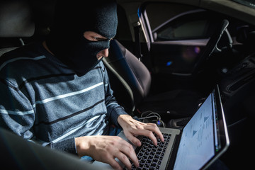 Thief with a laptop inside a car