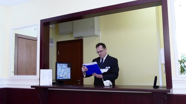 Apartment Concierge. Man looking to file with documents at the concierge desk.