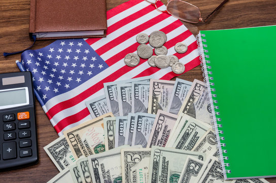usa flag with dollar bills and coins, calculator, notepad on table