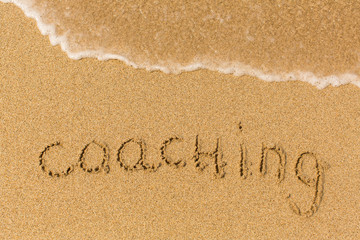 Coaching - written on sandy beach with the soft wave.