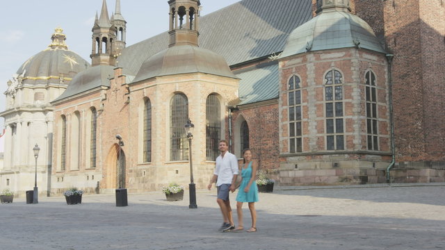 Sweden - urban couple in love holding hands in Stockholm city. People lifestyle video of two young adults dating walking by Riddarholmskyrkan, square, Riddarholm Church, Riddarholmen in Stockholm.