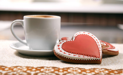 Dreaming of love. Closeup shot of a heart shaped red Valentine’s day cookie next to the cup of warm tea on the table