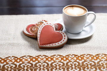 Love sweets. Closeup shot of a cup of a froth designed coffee and red heart shaped chocolate cookies