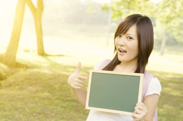 Fototapeta premium Asian female college student with blank chalkboard