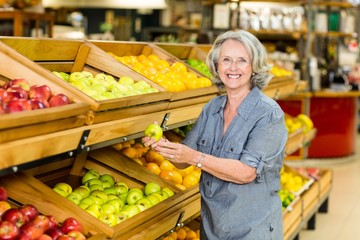 Smiling senior woman picking apple