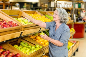 Smiling senior woman picking apples