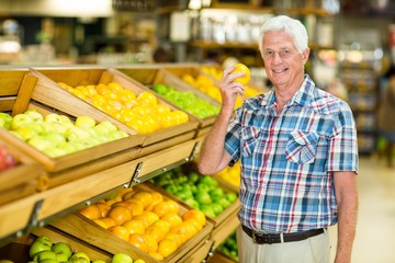 Smiling senior man holding orange