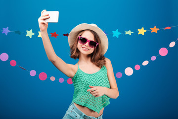 Cute playful little girl taking selfie with mobile phone
