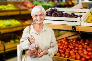 Senior woman holding bag with apple