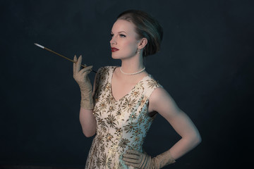Sensual retro 1950s posh fashion woman in gold dress holding cig