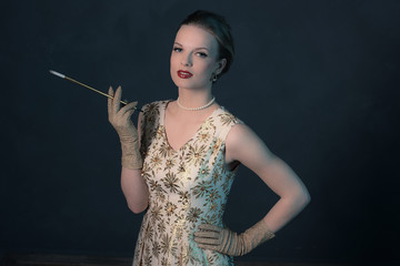 Sensual retro 1950s posh fashion woman in gold dress holding cig