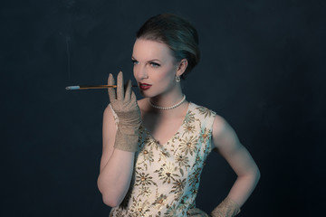 Obraz premium Sensual retro 1950s posh fashion woman in gold dress holding cig
