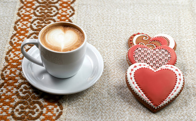 Sweetness served. Glazed red heart shaped cookies and a cup of coffee on Valentine’s day table at the cafe