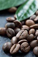 roasted coffee beans and leaves on a dark background, close-up