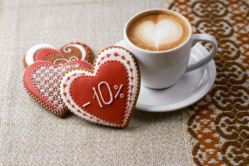 Sharing delicious. Top view shot of gingerbread heart shaped Valentine’s day cookies and a cup of coffee with froth design