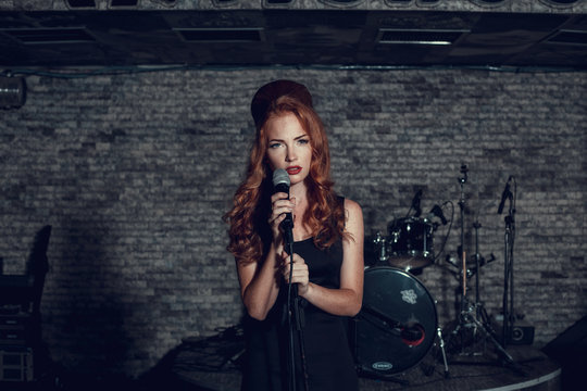 Young singer woman with red hair on the scene