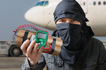 Terrorism concept. Terrorist in airport holds dynamite bomb in hand.