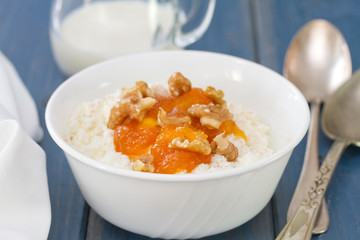 fresh cheese with pumpkin jam and nuts in bowl on blue wooden background