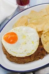 typical portuguese sausage alheira with fried egg and potato on dish on blue wooden background