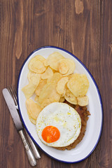 typical portuguese sausage alheira with fried egg and potato on dish on brown background