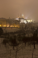 Night snowy foggy Prague City with gothic Castle, Czech republic