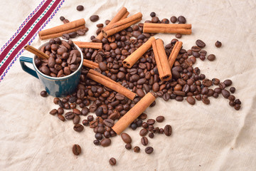 Cup with coffee beans cinnamon stick on jute background. Morning